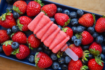 Fresh strawberry and blueberry ice cream. assorted fruits from the background.