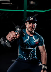 Portrait of young man lifting dumbbell in gym