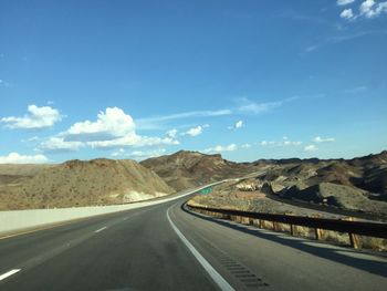 Empty road by mountains against sky