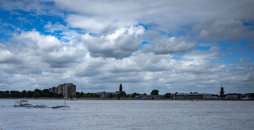 Scenic view of river by buildings against sky