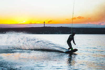 Wakeboarding man against sunset