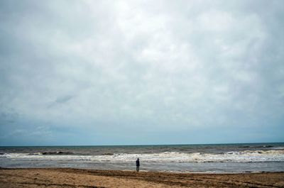 Scenic view of beach against cloudy sky