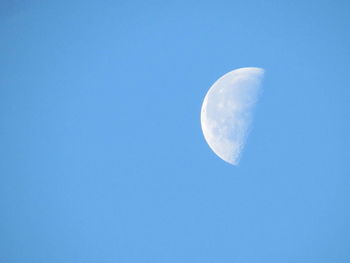 Low angle view of moon against clear blue sky