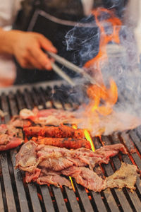 Cropped hand of man preparing food on barbecue grill