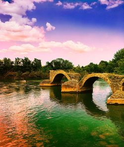 Arch bridge over river against sky