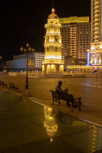 Man on illuminated street against buildings in city at night