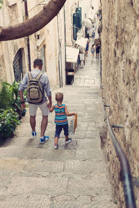 Full length rear view of father and son walking on steps in old town