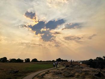 People on field against sky during sunset
