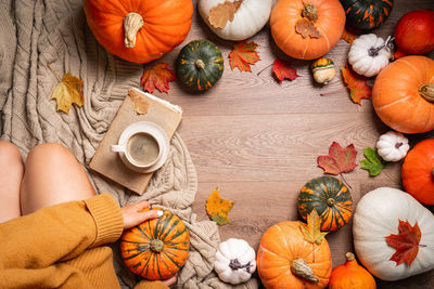 Midsection of woman with pumpkin on table