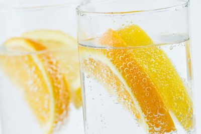 Close-up of lemon slices in glasses against white background