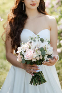 Midsection of bride holding bouquet