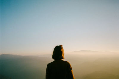 Rear view of man looking at mountain against sky