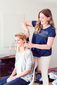 Young woman brushing sister's hair at home