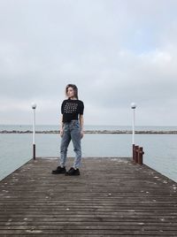 Rear view of woman walking on pier over sea against sky