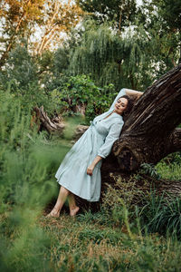 Nature and mental health. barefoot woman in a dress is resting near the trees in nature barefoot