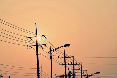 Low angle view of electricity pylon at sunset