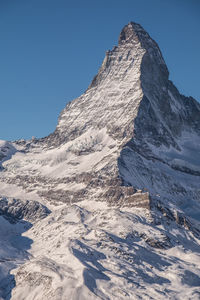 Low angle view of snowcapped mountains against clear sky