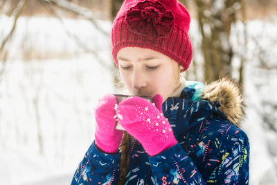 Portrait of woman holding hat during winter