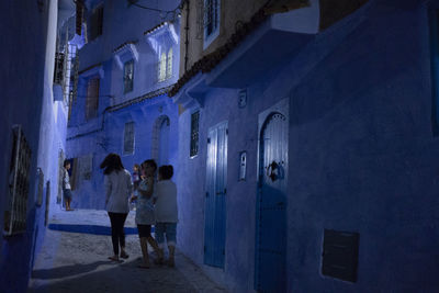 Rear view of people walking on building at night