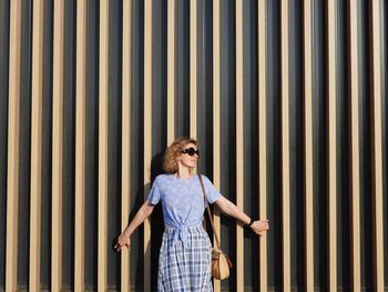 Portrait of young woman standing against wall