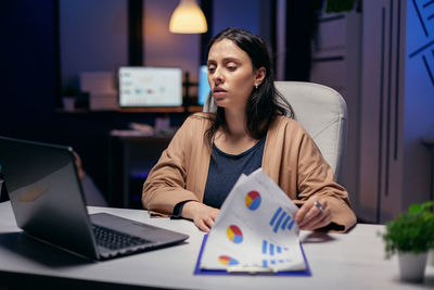 Young woman using mobile phone while sitting on table