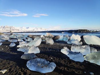 Snow covered rocks against sky during winter