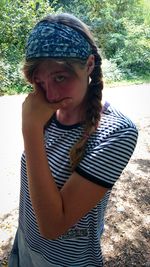 Portrait of young woman standing against tree