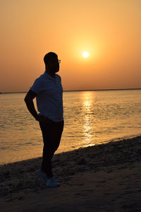 Full length of man standing on beach during sunset