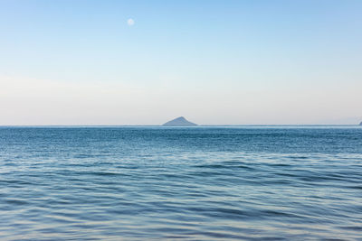 Small island with full moon in bright summer day