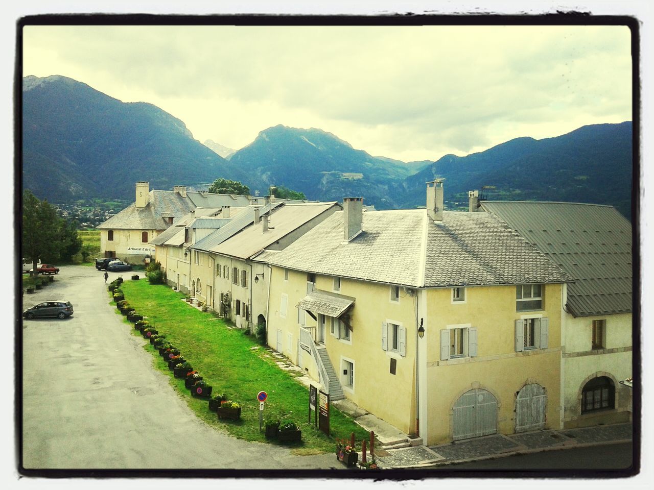 building exterior, architecture, mountain, built structure, transfer print, sky, house, transportation, auto post production filter, road, street, mountain range, residential structure, car, cloud - sky, town, residential building, the way forward, cloud, land vehicle