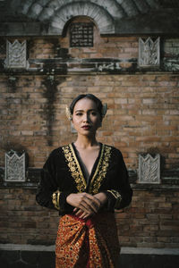 Portrait of woman in traditional clothing standing against building