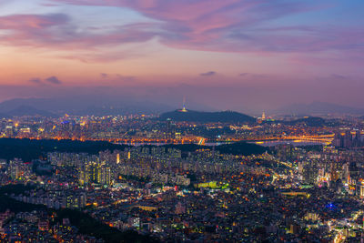 Illuminated cityscape against sky during sunset