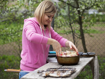 Woman preparing food at table outdoors