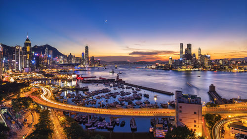 High angle view of illuminated bridge over harbor in city during sunset