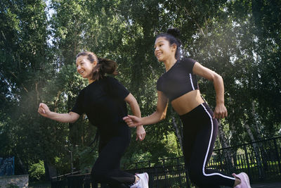 Girl in sportswear on a sunny summer day on the embankment in the park doing fitness and stretching