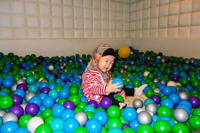 Girl wearing hijab playing in multi colored ball pool