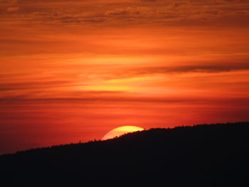 Scenic view of silhouette landscape against orange sky