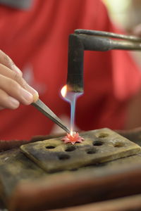 Midsection of person holding candles on barbecue grill