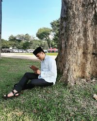 Side view of young man reading book while sitting on grass