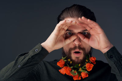 Portrait of young man holding flowers against black background