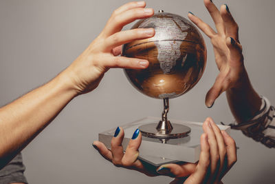 Close-up of people holding globe over blue background
