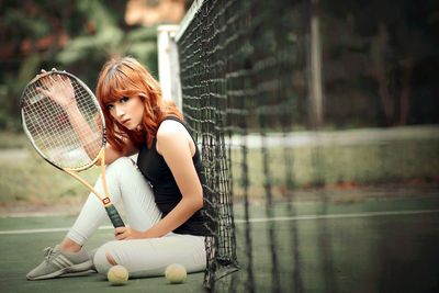 Young woman is playing tennis with racket and ball in hands