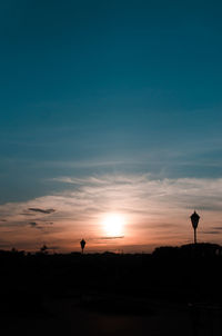 Silhouette person on street against sky during sunset