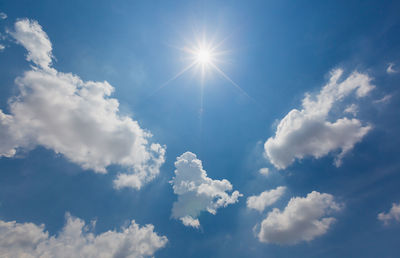 Low angle view of sunlight streaming through clouds