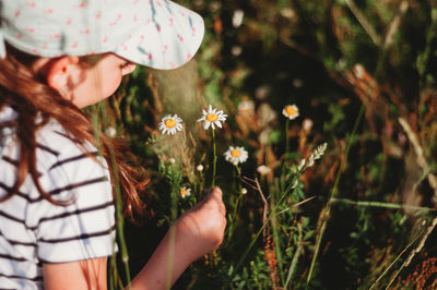 Close-up of girl looking at flower on field