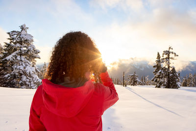 Woman standing on snow covered field against sky