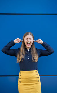 Portrait of smiling young woman standing against blue sky