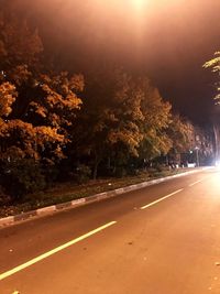 Road by trees against sky in city