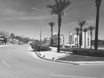 Road by buildings in city against sky