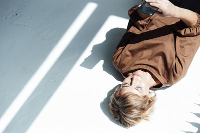 Businesswoman using mobile phone while lying on floor in office